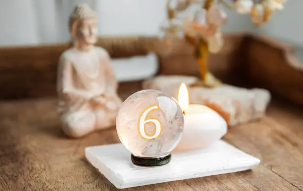 Number six on Gemstone sphere or crystal balls known as crystallum orbis and orbuculum. Natural clear quartz ball on stand on wood tray in home. Predictions concept.