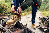 Teenage boy tying shoelace of hiking boots in High Tatra Mountains an autumn day
