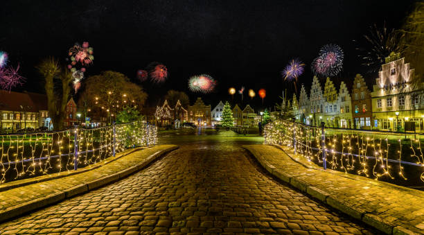 Charming town bathed in festive lighting and fireworks, creating a romantic atmosphere for New Year's Eve with the spectacular display of colors and lights. Friedrichstadt at night during the New Year