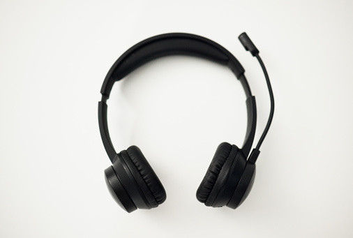 Headphones, closeup and technology, microphone for communication and sound gear on white background. Audio, radio and music, listening for podcast or wireless tech for gaming or free hand phone call