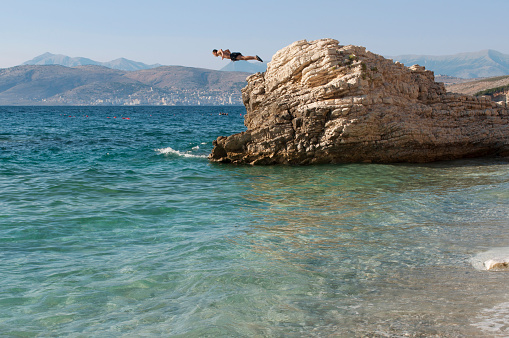 A Man Dives from a Rock Formation at the Beautiful Pulebardha Beach, in Southern Albania, During Summer. Ksamil Province, Albania