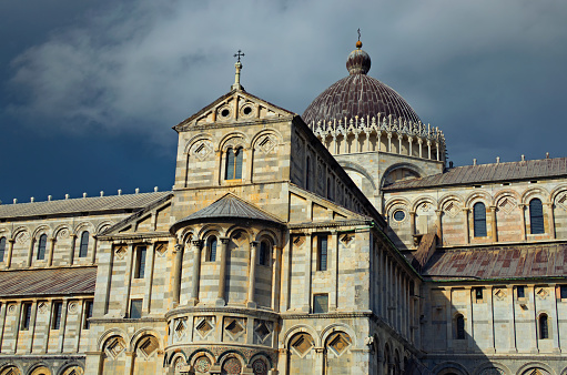 Detailed view of ancient Pisa Cathedral against stormy sky and gloomy clouds. Notable landmark of Pisa, Italy. UNESCO World Heritage Site.