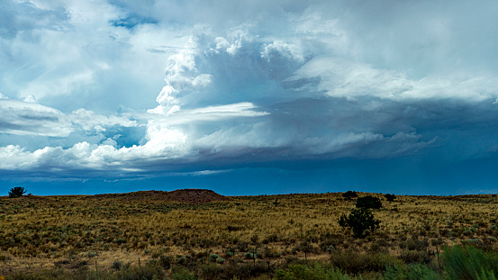 An awe-inspiring storm cloud looms and builds over the desert landscape