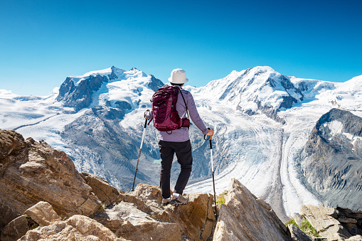 Rear view of female hiker enjoying the view of the Grenz glacier from a view point Gornergrat, Zermatt, Switzerland