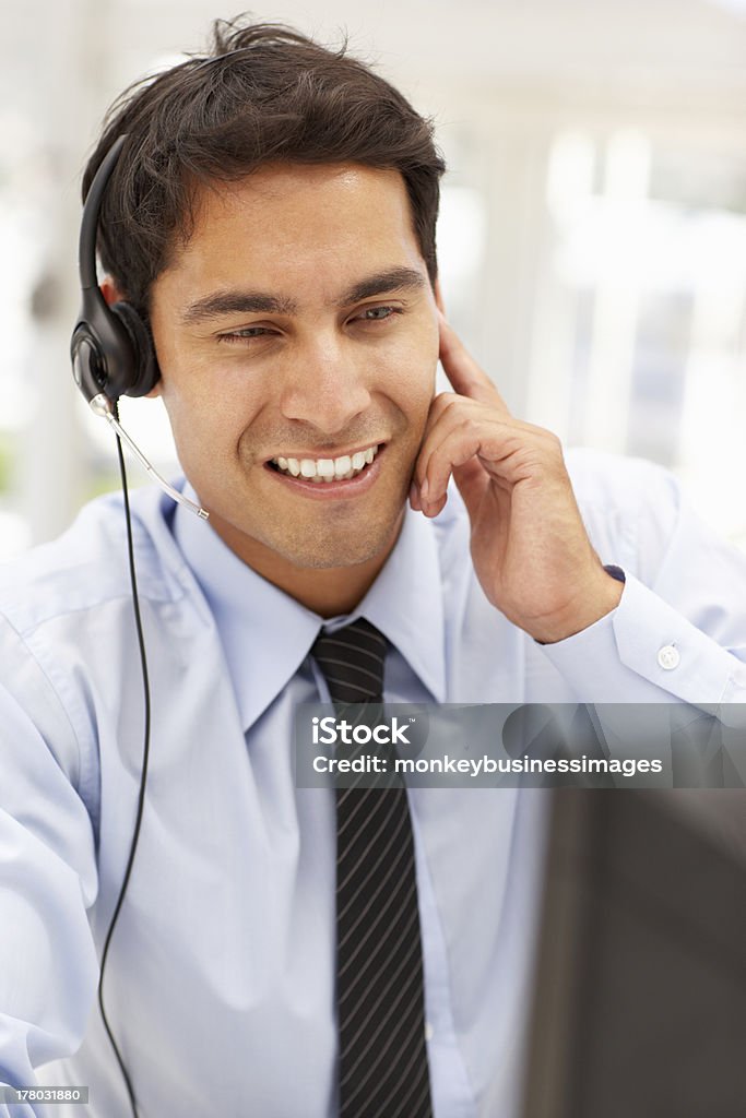 Businessman wearing headset Businessman wearing headset sitting at desk using computer Men Stock Photo