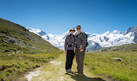 Switzerland travel- Portrait of Senior couple hiking the Swiss alps near the Matterhorn and the Gorner glacier in the background