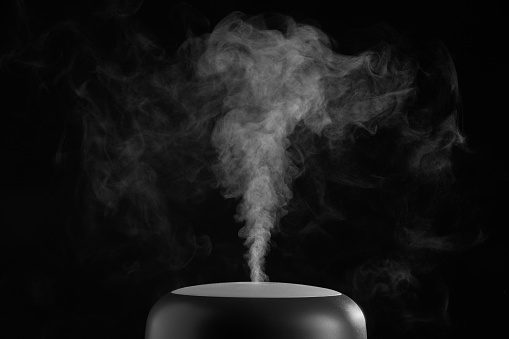 Horizontal shot of air humidifier on black background. White steam close-up. The concept of humidification of the air. Photo with copy space.