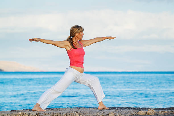 istock Woman Practicing Yoga by the Ocean 178032414