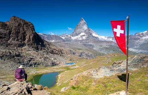 Switzerland travel: Female hiker taking a picture of the view of Riffelsee and the Matterhorn in the mountains of Zermatt.