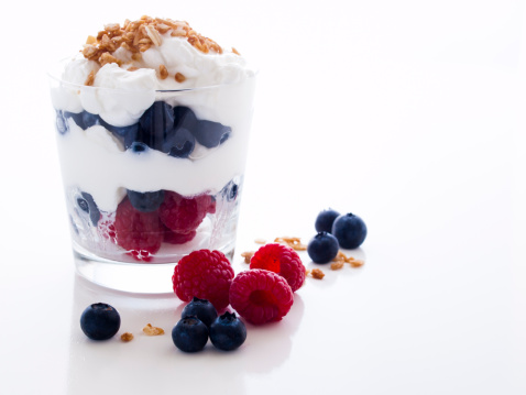 Delicious fruit, greek yogurt and granola parfaits on white background