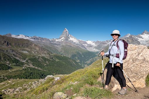Switzerland Travel - Woman hiking a trail in the Zermatt area of the Swiss Alps in summer.