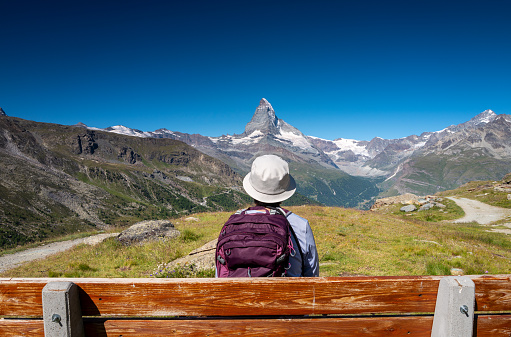 Switzerland travel - woman hiking the Swiss Alps stops to enjoy the view of the Matterhorn.