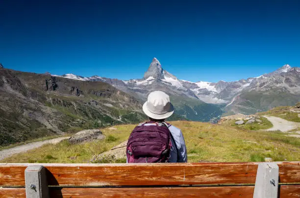 Switzerland travel - woman hiking the Swiss Alps stops to enjoy the view of the Matterhorn.