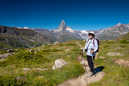 Switzerland travel - Senior woman hiking the Swiss Alps view of  the Matterhorn in the background.