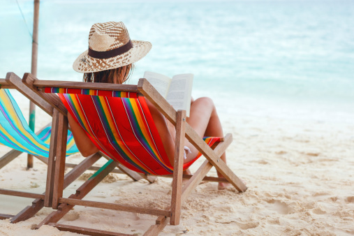 Back view of a young girl relaxing on a beach chair along the shoreline