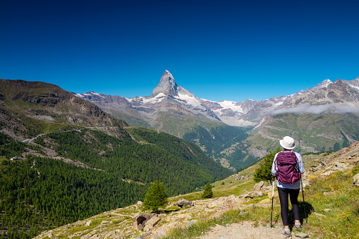 Backpacker with backpack enjoying the turquoise Lago di Sorapiss 1,925m altitude (mountain lake) view as he has mountain walk in Dolomite Mountains, Italy. Active people in nature concept.