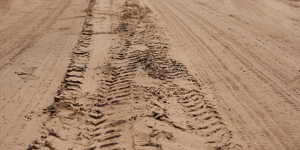 Horizontal shot of traces of protectors of heavy trucks on the sand.
