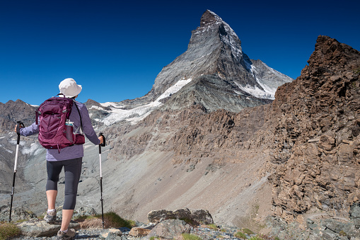 Switzerland travel - Senior woman hiking the Swiss Alps on trails with great views of the Matterhorn.