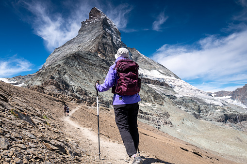 Switzerland travel - Senior woman hiking the Swiss Alps on trails with great views of the Matterhorn.