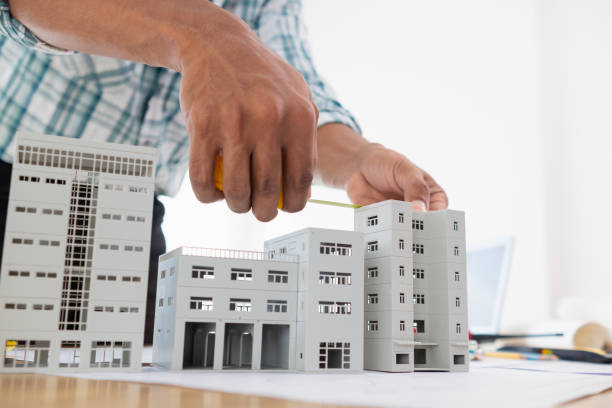 istock architect is preparing house model and construction plans on blueprints for construction engineering team to review before construction engineering team constructs building according to the drawings. 1780348400