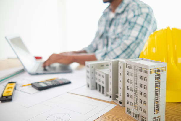 istock architect is preparing house model and construction plans on blueprints for construction engineering team to review before construction engineering team constructs building according to the drawings. 1780349516