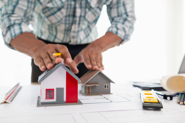 istock architect is preparing house model and construction plans on blueprints for construction engineering team to review before construction engineering team constructs building according to the drawings. 1780349526