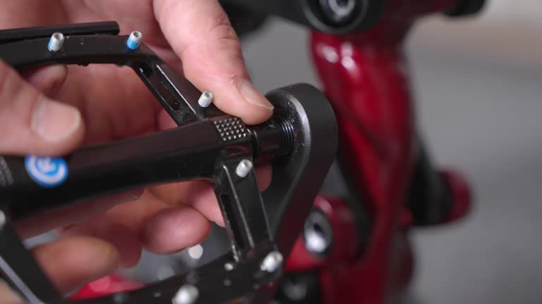 Hand installing flat pedal with pegs into crank arm of brand new mountain bike by bycicle mechanic. Closeup