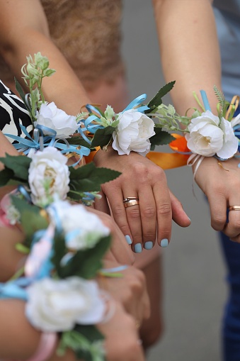 The bride and bridesmaids stand in a circle and hold hands with white flower bracelets, corsages. Bachelor girls party.