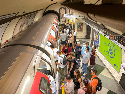 London, England, UK - 22 August 2023: Crowd of people getting on an  underground train on the London Tube