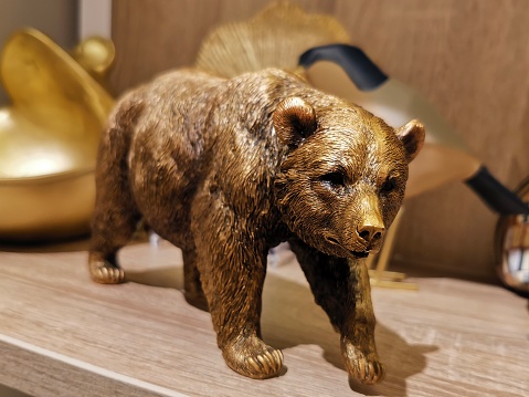 On a wooden shelf there is a statuette of a bronze walking bear
