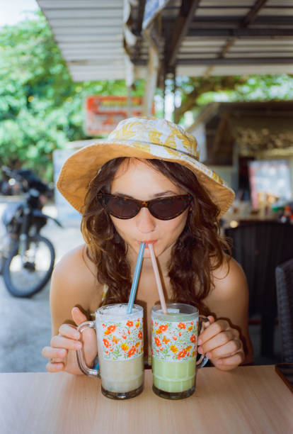 istock Woman  in sunglasses drinking smoothies from two straws during beach vacation 1780366106