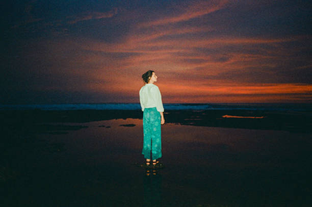 Woman standing on the beach at sunset. Shot on camera film with flash
