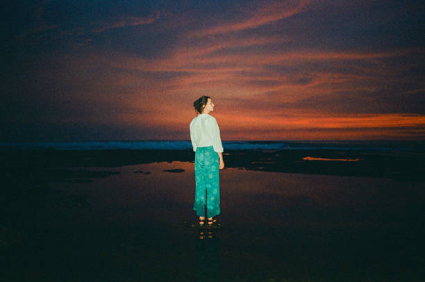mulher em pé na praia ao pôr do sol - sunset beach flash - fotografias e filmes do acervo