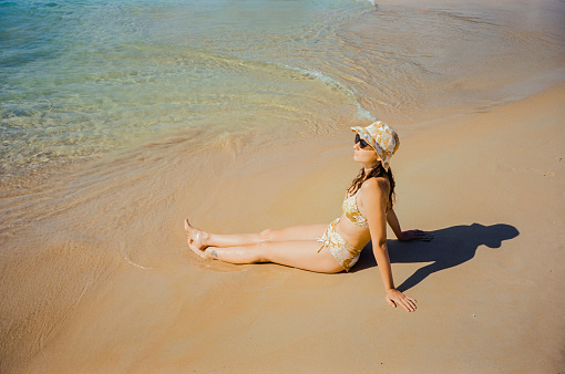 Carefree woman in sunglasses and sunhat  relaxing on beach during vacation