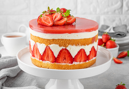 Fraisier mousse cake. Strawberry cake with sponge cake, mousse and jelly on a gray concrete background. Summer dessert. Selective focus. Copy space.