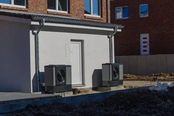 Air source heat pumps installed on the exterior facade of the multifamily residential during construction. Sustainable heating solutions for new building.Construction site of multifamily residential.