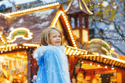 Little girl dressed as a snow princess on Christmas market.