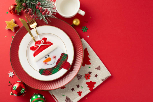 istock New Year's children's party table arrangement. Top view image showcasing adorable plate setting, gold cutlery in special pocket, mug, napkin, baubles, candle, snowflakes, fir twig, mistletoe berries 1780388772