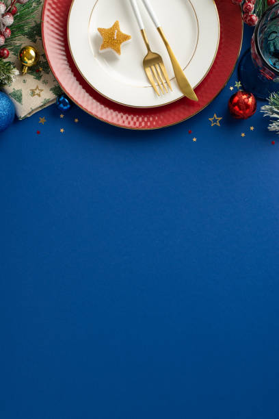 istock Luxurious restaurant table setup for New Year celebration from top view vertical perspective, displaying plates, cutlery, glass, ornaments, confetti, frosted fir branches, mistletoe, blue backdrop 1780388792