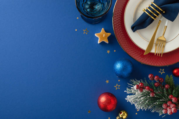 istock Top view glamorous holiday table arrangement, featuring glistening tableware, napkin ring, baubles, and star-shaped candle, set against a wintry blue backdrop with space for your text or advertisement 1780388862
