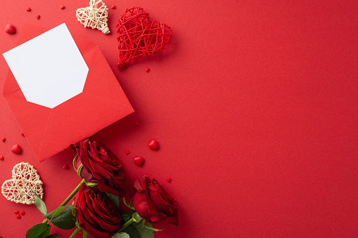 Create a loving atmosphere for Valentine's Day using an overhead view of rattan hearts, red roses, a love letter, sweet sprinkles, and red background for your words