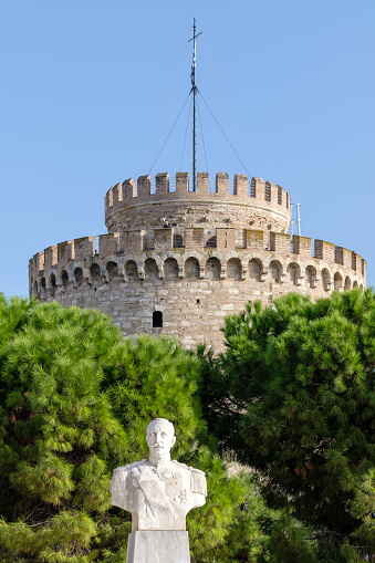 Thessaloniki, Greece - September 22, 2023 : View of the bust of admiral  Nikolaos Votsis and the famous White Tower in the background in Thessaloniki Greece