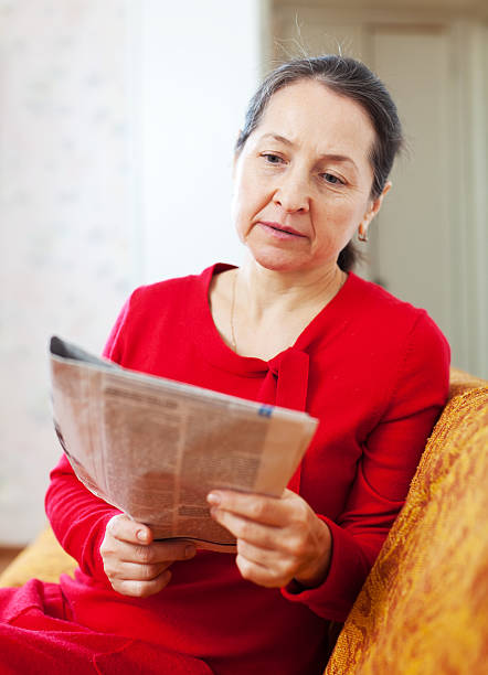 istock wistful woman reading newspaper 178039497