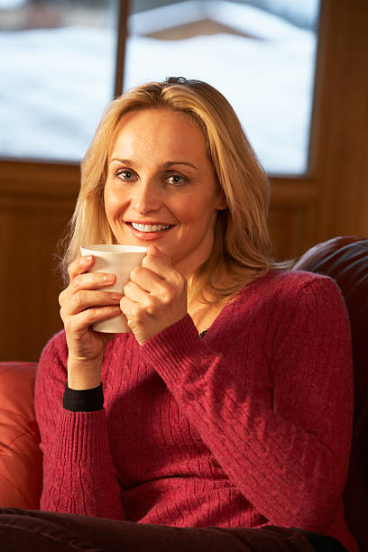 istock Middle Aged Woman Relaxing With Hot Drink On Sofa 178039598