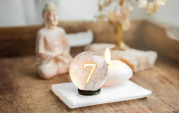 Number seven on Gemstone sphere or crystal balls known as crystallum orbis and orbuculum. Natural clear quartz ball on stand on wood tray in home. Predictions concept.