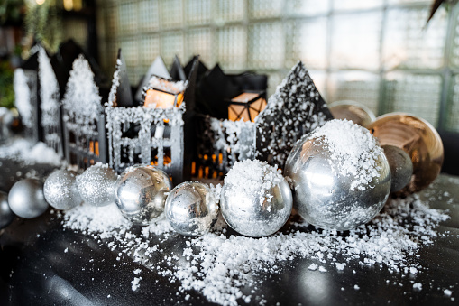 Silver shiny Christmas balls, cardboard houses covered with artificial snow. New Year and Christmas, winter time, preparations for the holiday. High quality photo