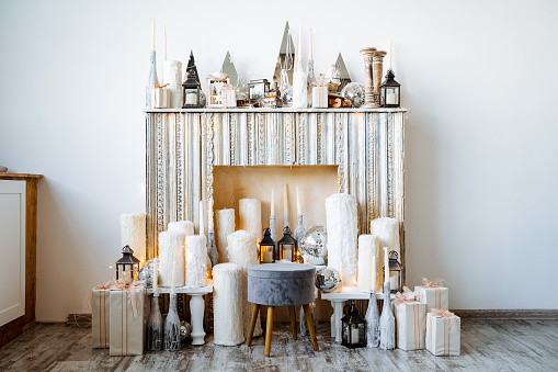 Interior shot in the studio. Unburned fireplace on which there are many candles of various sizes, there are gift boxes everywhere. New Year and Christmas. High quality photo
