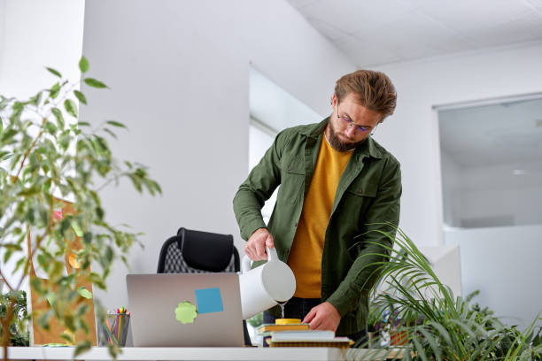 istock young pleasant guy stand behind office desk pouring tea into cup, break time at work 1780411955