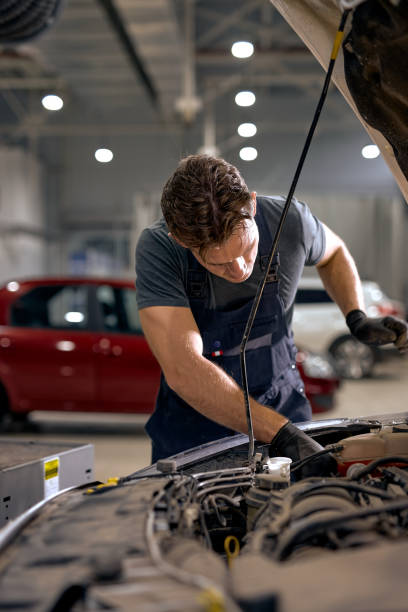 concentrated auto mechanic male working alone repairing engine of the car in hood concentrated auto mechanic male working alone repairing engine of the car in hood, looking at details. caucasian male mechanic is working in car service, alone in modern clean workshop muster station stock pictures, royalty-free photos & images