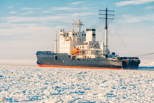 Winter shipping. Big cargo ship in frozen ice sea fairway